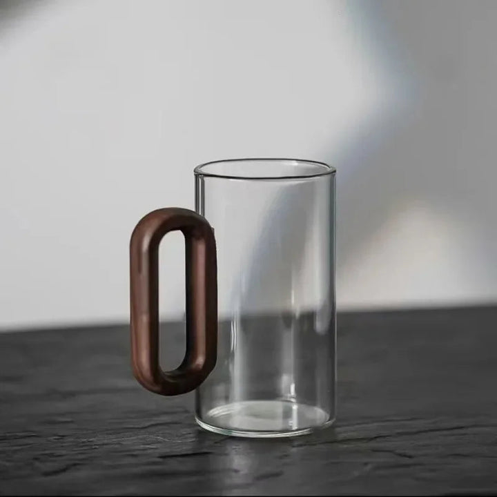 Clear borosilicate glass coffee mug, showing off a rich walnut handle. Elegant and durable kitchenware.