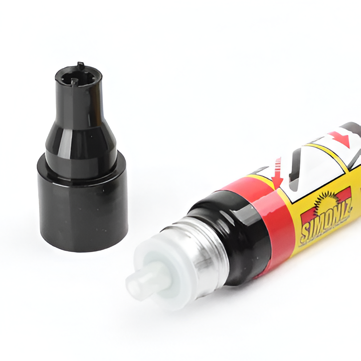 Hand holding car scratch repair pen, precisely fixing a vehicle paint scratch. Quick auto surface damage remover.