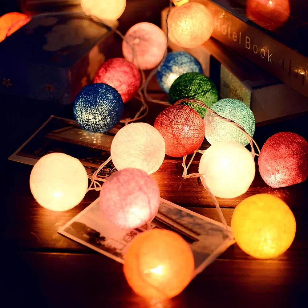 Warm white cotton ball string lights illuminating a bookshelf, for a cozy reading nook ambiance.