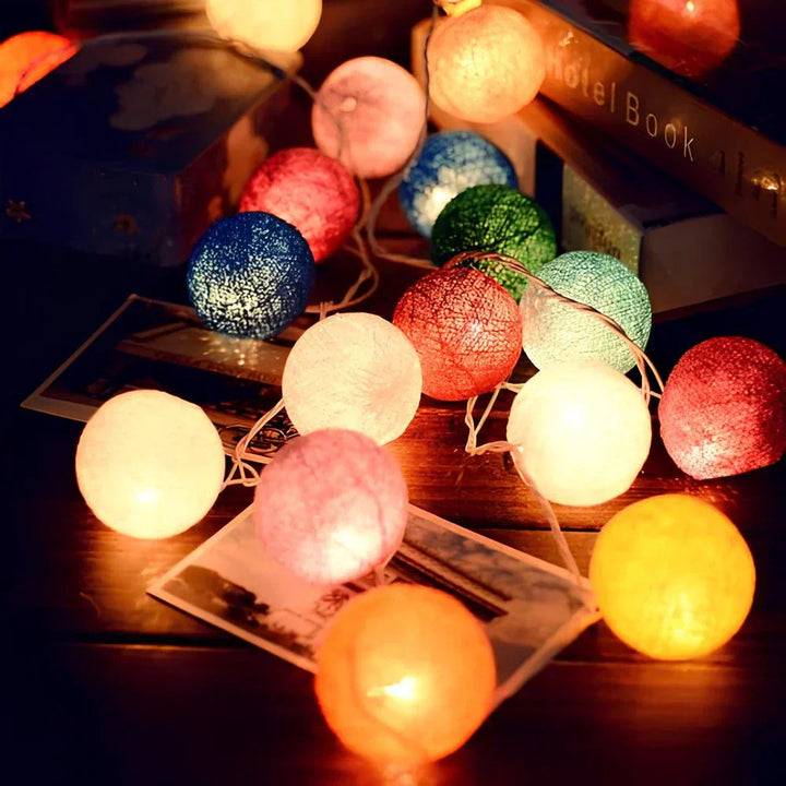 Warm white cotton ball string lights illuminating a bookshelf, for a cozy reading nook ambiance.