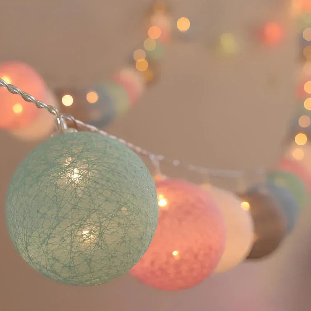 Hand holding decorative cotton ball string lights, demonstrating their portable and lightweight design.