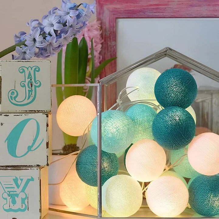Decorative cotton ball lights arranged in a glass vase, creating a unique table centerpiece.