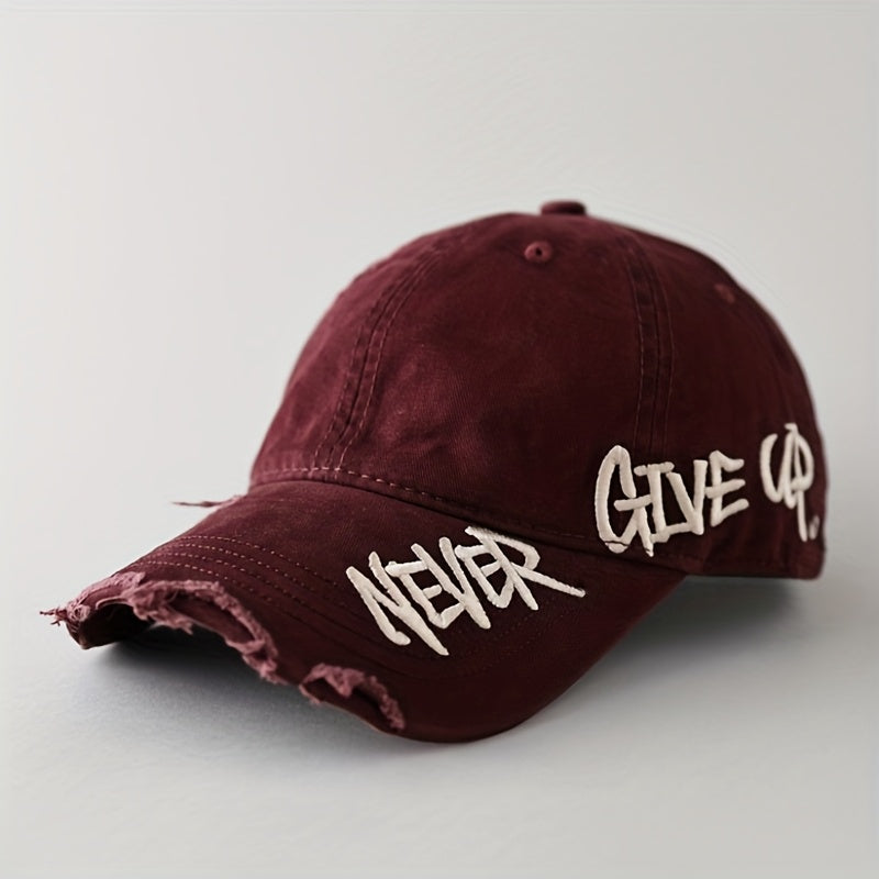 Close-up of a distressed denim cap, "Never Give Up" text embroidered in graffiti style. Unisex casual hat.