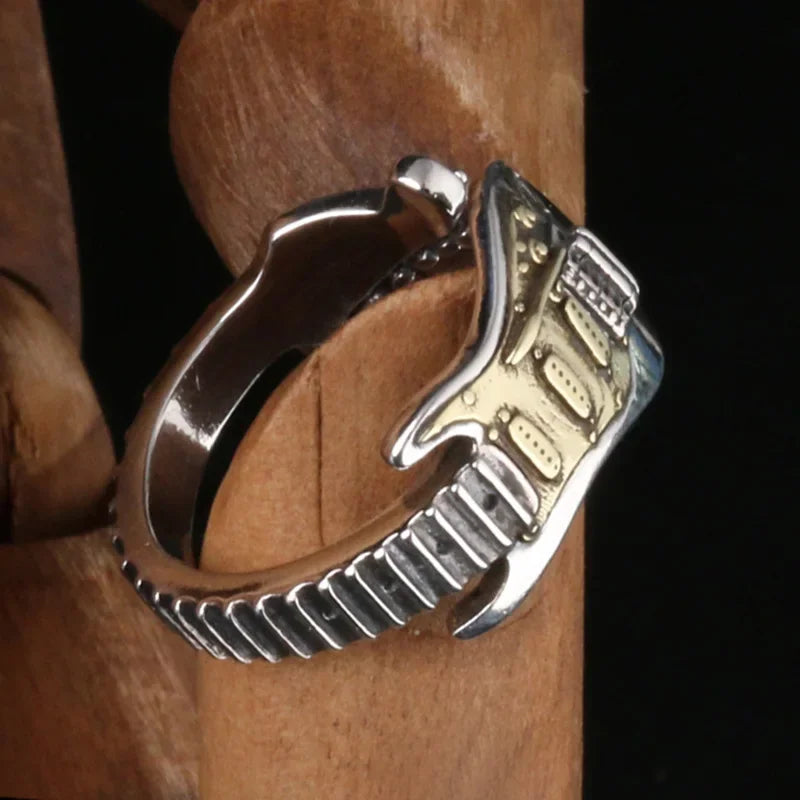 Close-up of detailed electric guitar pendant & ring, vintage-style metal, unisex rock music accessory.