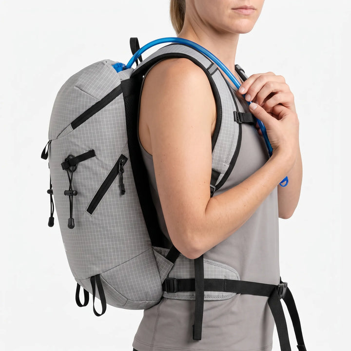 Hiker wearing a lightweight hydration backpack on a mountain trail, ready for adventure.