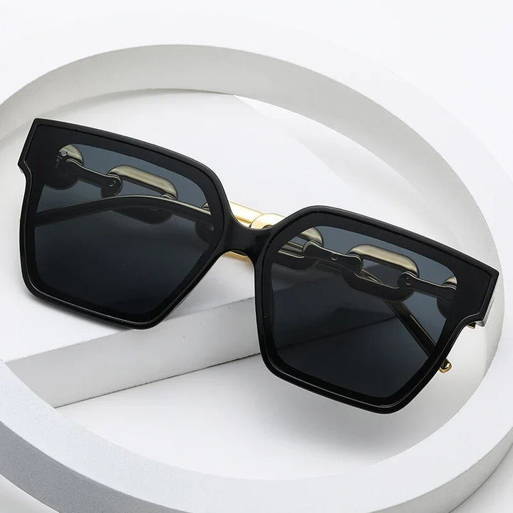 Fashionable oversized sunglasses featuring a sleek metal frame and distinctive chain temples for a chic, statement look.