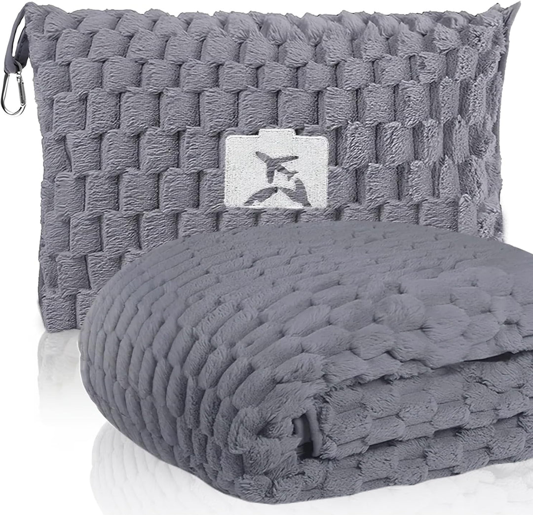 Woman using gray flannel travel blanket and pillow on an airplane, comfortable travel gear