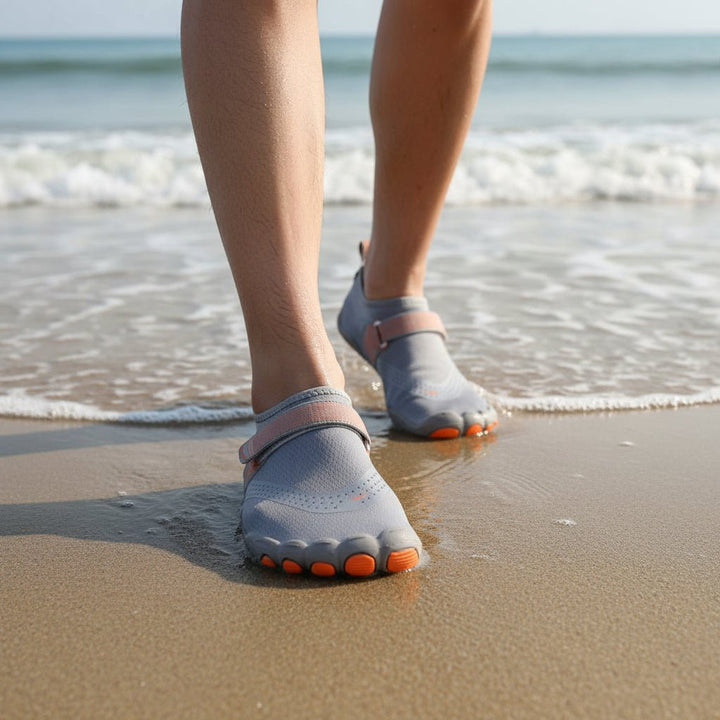 Person wearing black unisex water shoes on a sandy beach. Ideal for swim, surf, & water activities.