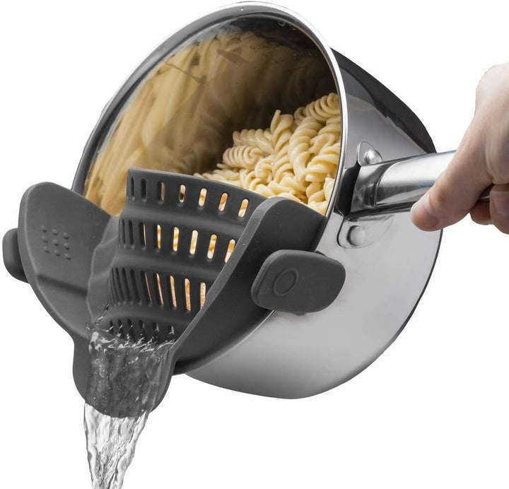 Unisex silicone clip-on strainer attached to a silver pot, draining pasta