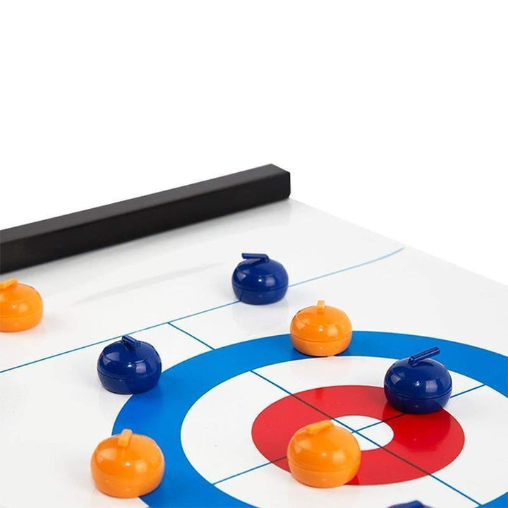 Two hands preparing to slide a stone in the Tabletop Curling strategy game, highlighting engaging indoor play.