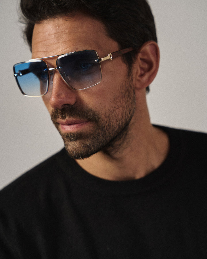 Urban fashion model wearing unisex square sunglasses with woodgrain arms & gold frame.