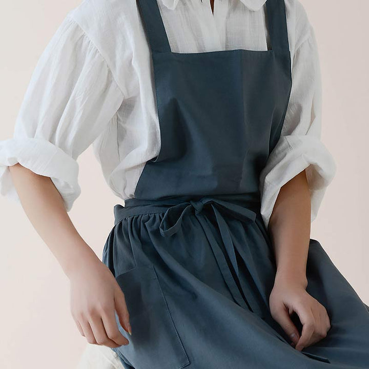 Protective waterproof cotton kitchen apron with spacious pockets for utensils.