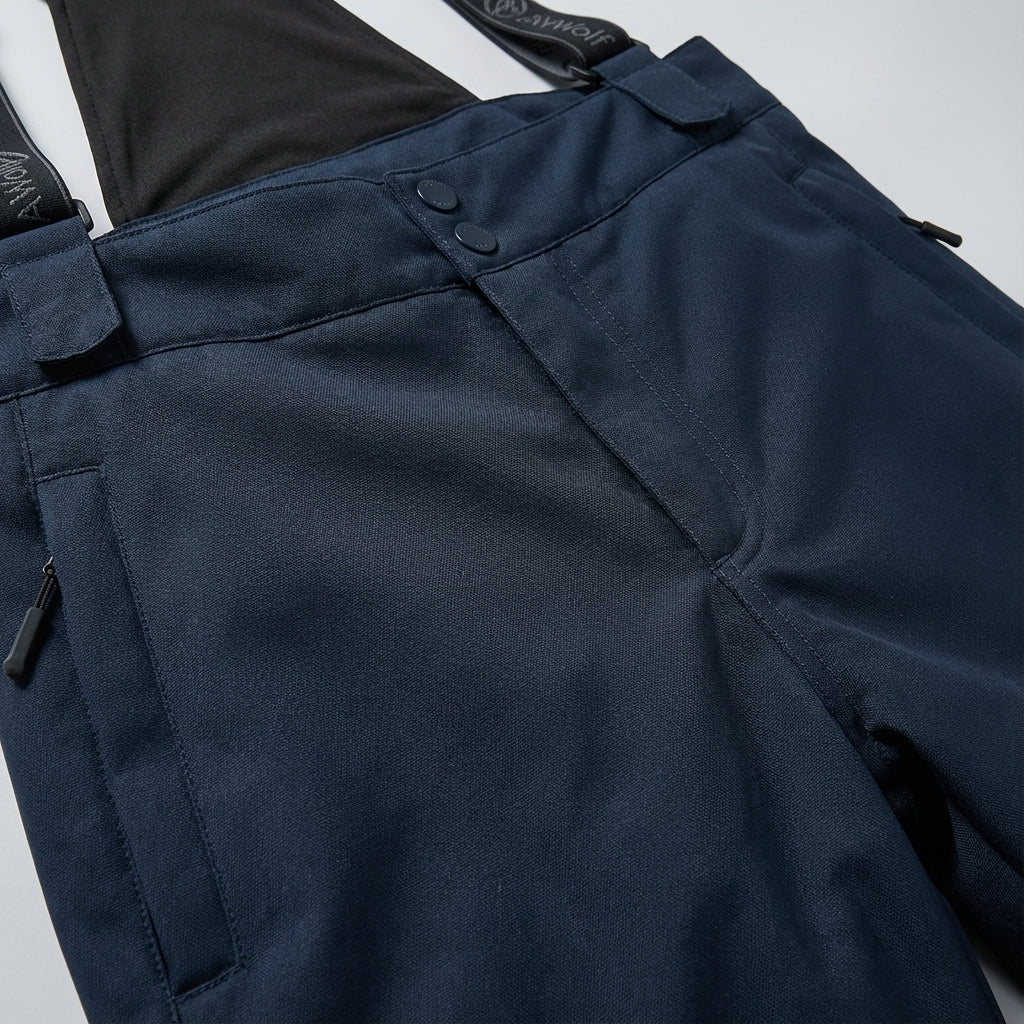 Model wearing black unisex waterproof ski trousers with braces on snowy mountain