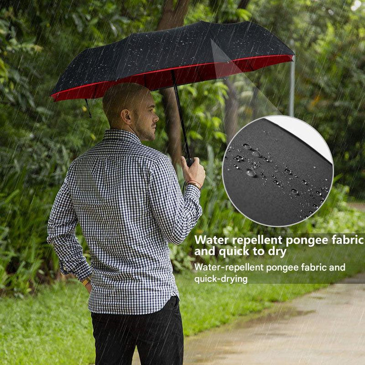 Unisex AeroShield compact travel umbrella protecting a person from rain and wind on a city street