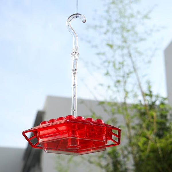 Decorative colored hummingbird feeder with built-in ant moat, perfect for outdoor wildlife & garden decor.