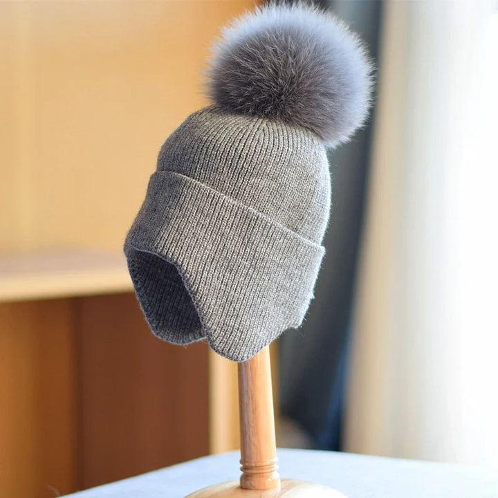 Stylish black alpine pom beanie. Unisex knit hat, perfect for winter cold. Warm and trendy headwear.