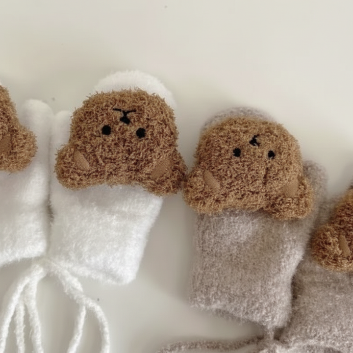 Soft pink knitted baby mittens with connecting cord, ideal for cold weather.