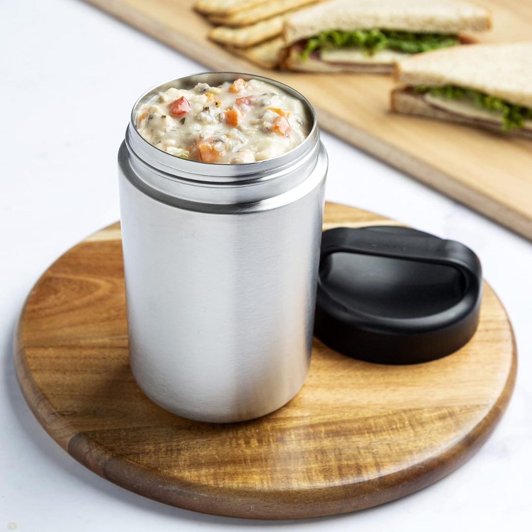 Person holding a WarmCarry stainless steel insulated food container with handle outdoors