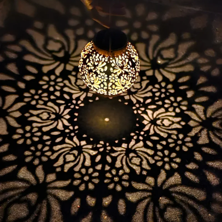 Decorative solar-powered LED hanging lantern illuminating a garden, an energy-saving outdoor accent light.