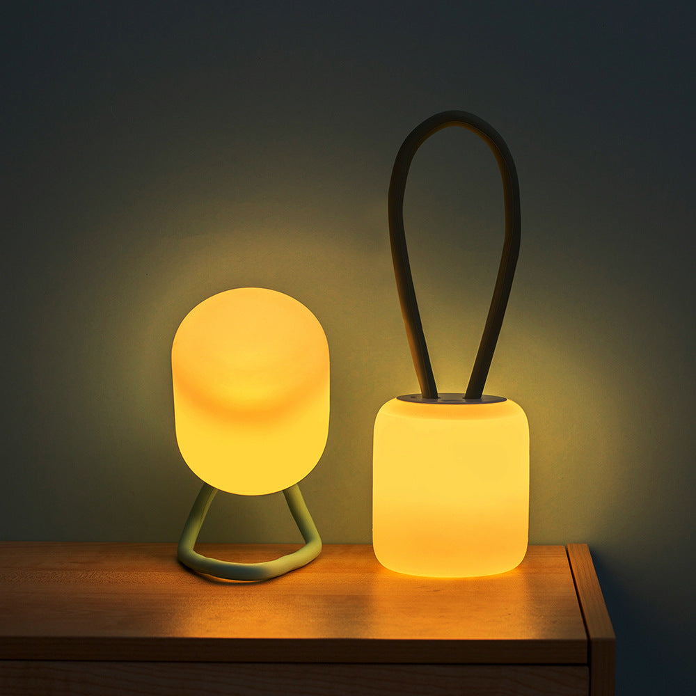 Hand holding the Softora Portable LED Night Lamp, showcasing its small size and portability for camping or outdoor use