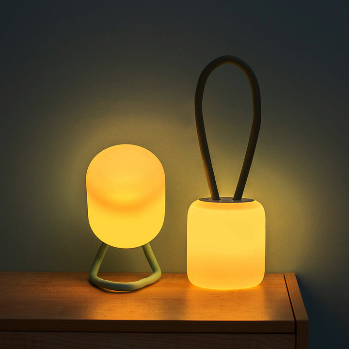Hand holding the Softora Portable LED Night Lamp, showcasing its small size and portability for camping or outdoor use