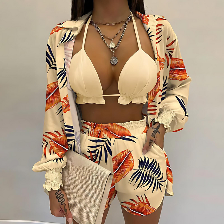 Women's resort wear: green tropical bikini top, high-waisted shorts & long-sleeved cover-up blouse.