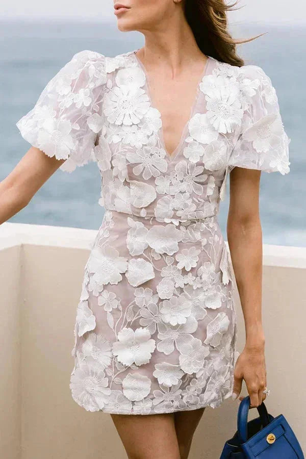 Close-up of a women's mini dress, showcasing delicate 3D floral appliqué and trendy puff sleeves for parties.