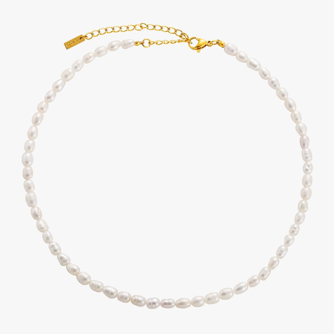 Women's adjustable freshwater pearl choker, elegant gold jewelry, delicate design on display stand.