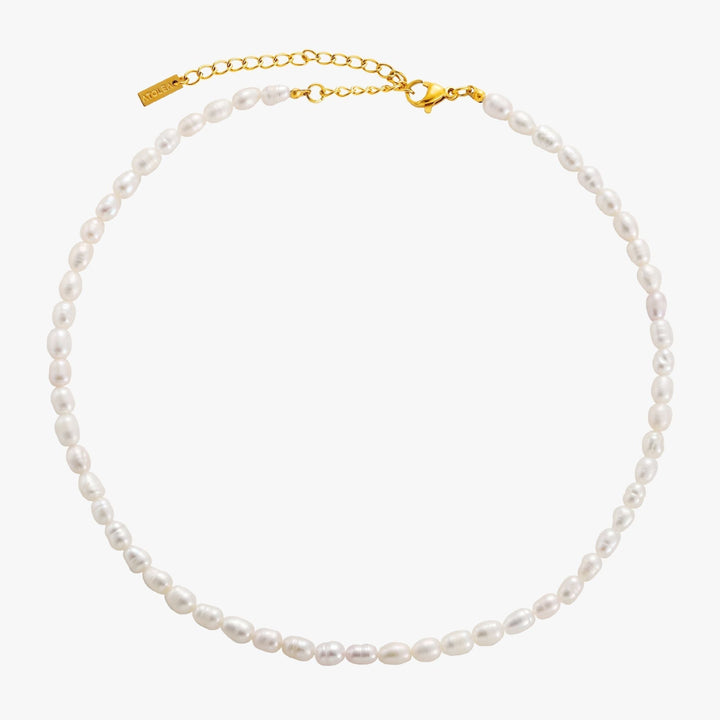 Women's adjustable freshwater pearl choker, elegant gold jewelry, delicate design on display stand.