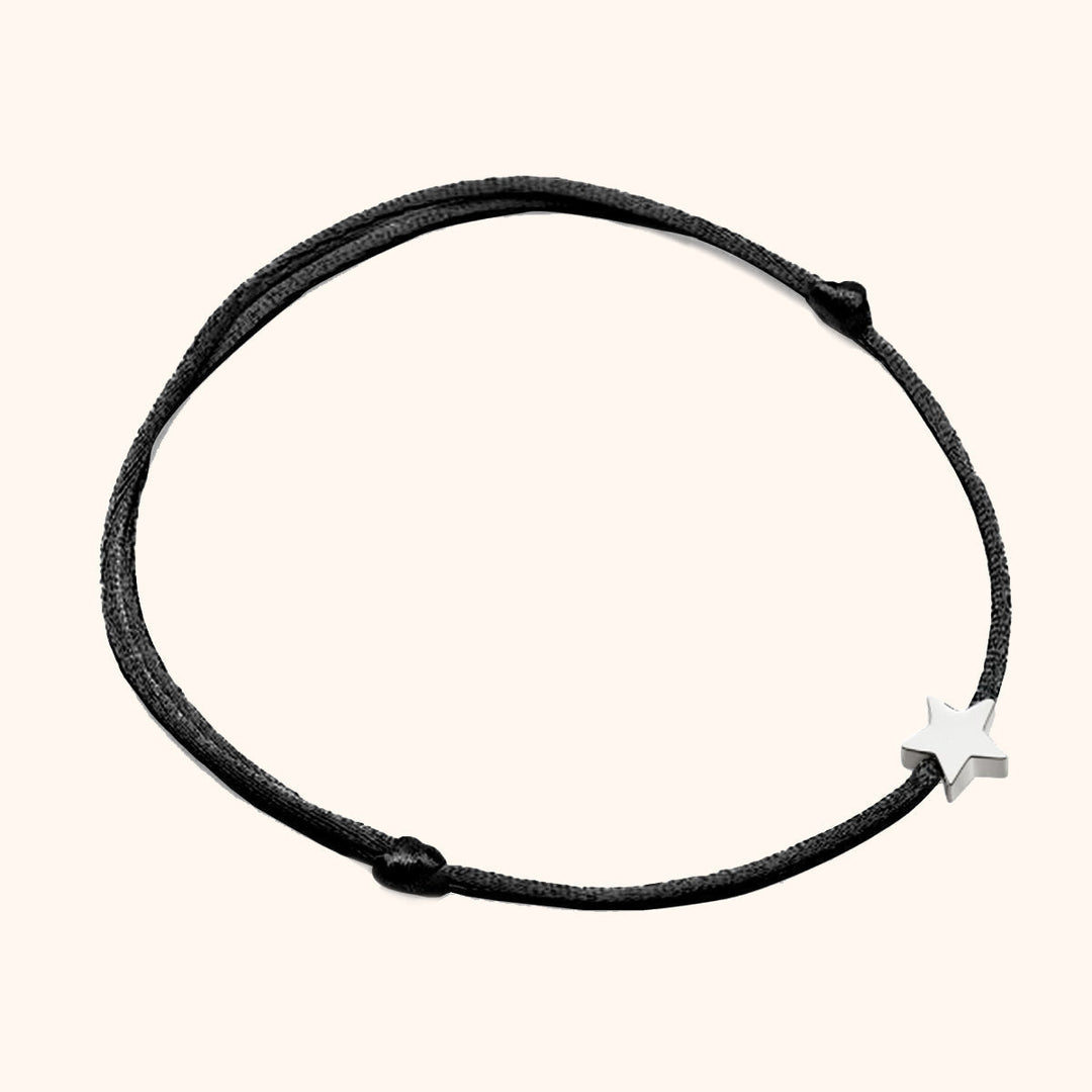 Close-up of a delicate metal star charm on an adjustable nylon cord women's bracelet.