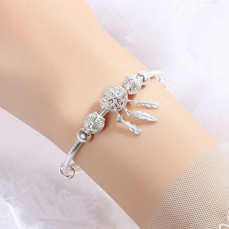 Close-up of a women's adjustable sterling silver dreamcatcher bracelet, showing intricate feather and web details.