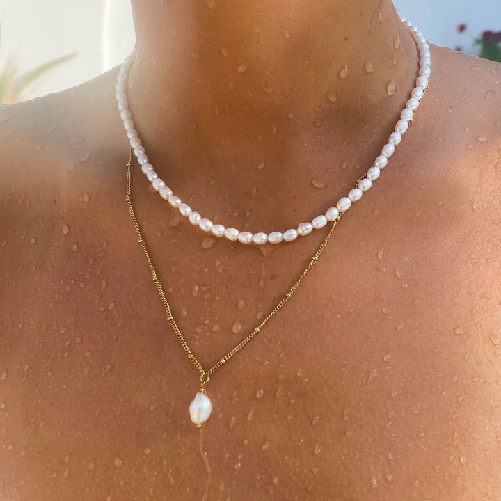 Silver-tone delicate chain necklace with a striking baroque pearl pendant, versatile fashion.