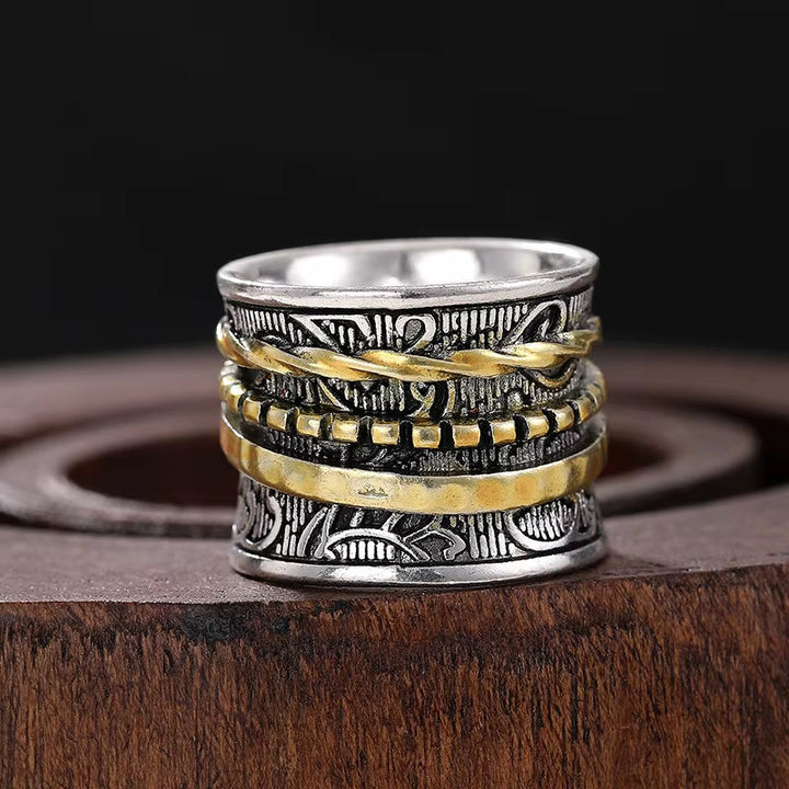 Close-up of a vintage women's gold/silver ring, featuring a textured artisan gilded flora wide band design.