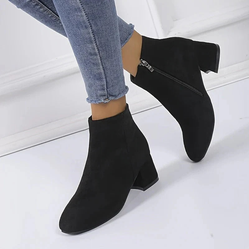 Sleek women's ankle boots, dark-colored, with a chunky block heel & easy-on side zip, great for casual outfits.