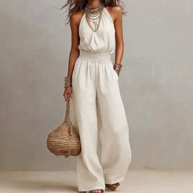 Women's black halter neck wide leg jumpsuit with smocked waist and side pockets. Elegant, casual, & resort wear.