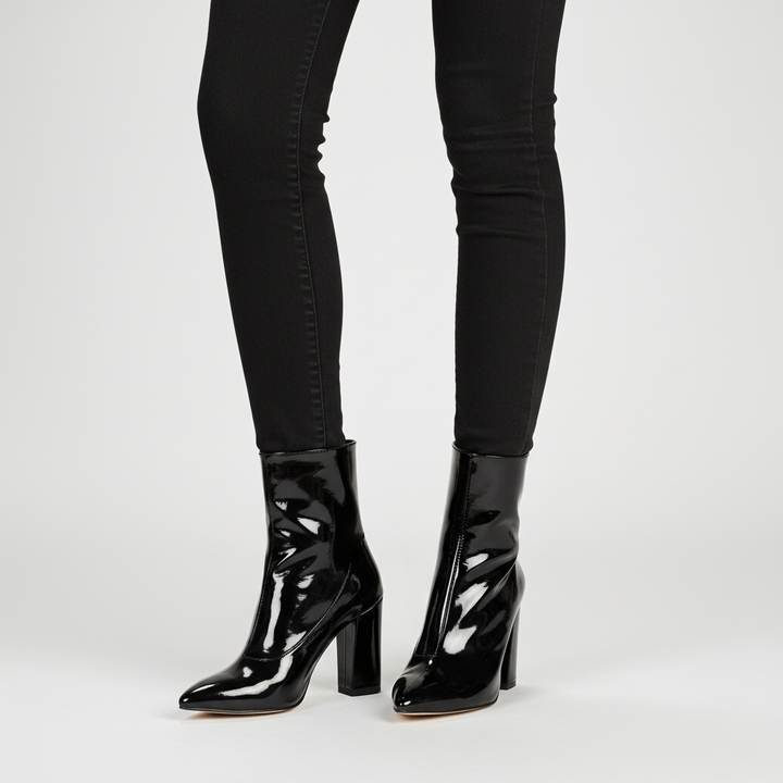 Close-up of shiny black patent leather ankle boots for women, showcasing the block heel and sophisticated design.