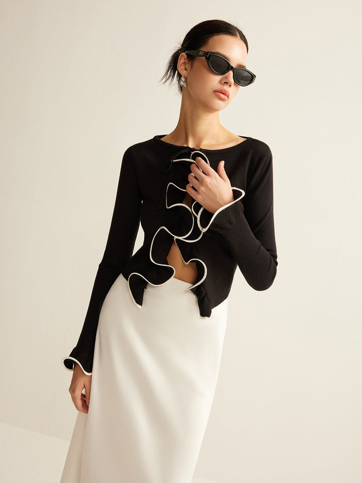 Close-up of women's black skinny ruffle cardigan. Features delicate ruffles & an elegant, fashionable design.