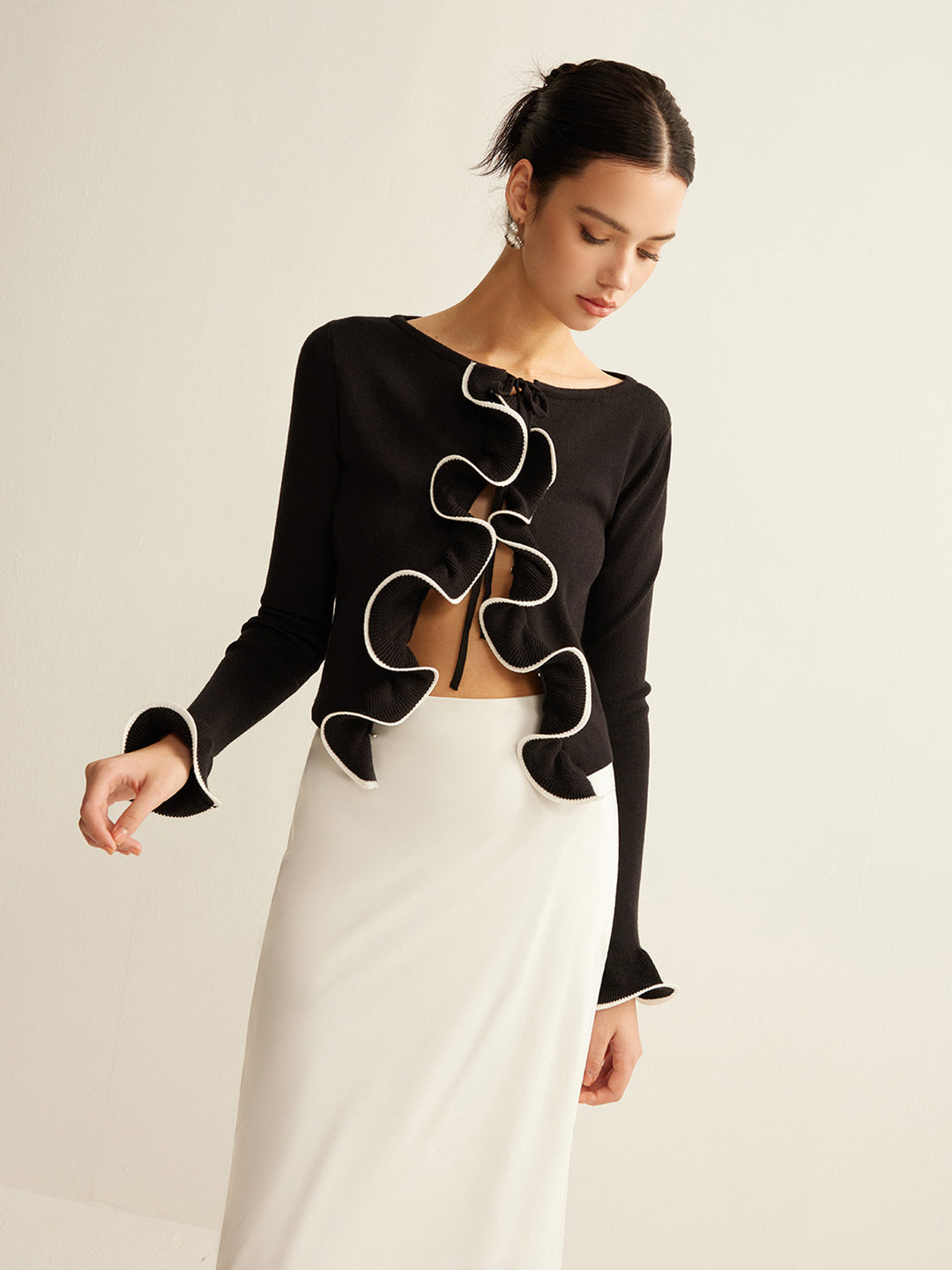 Model wearing a women's black skinny ruffle cardigan. Shows versatile layering & elegant, comfortable style.