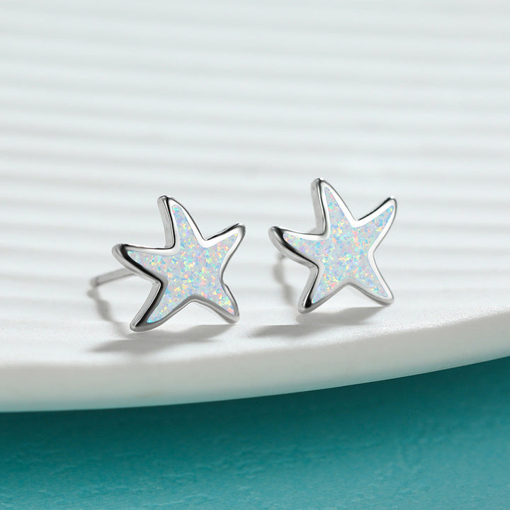 Close-up: Women's blue opal starfish earrings, intricate detailing, silver finish.