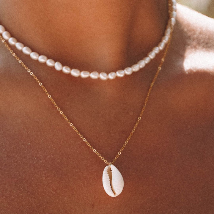 Women's boho chic cowrie shell pendant necklace, perfect for beach fashion & summer style. Adjustable gold chain.