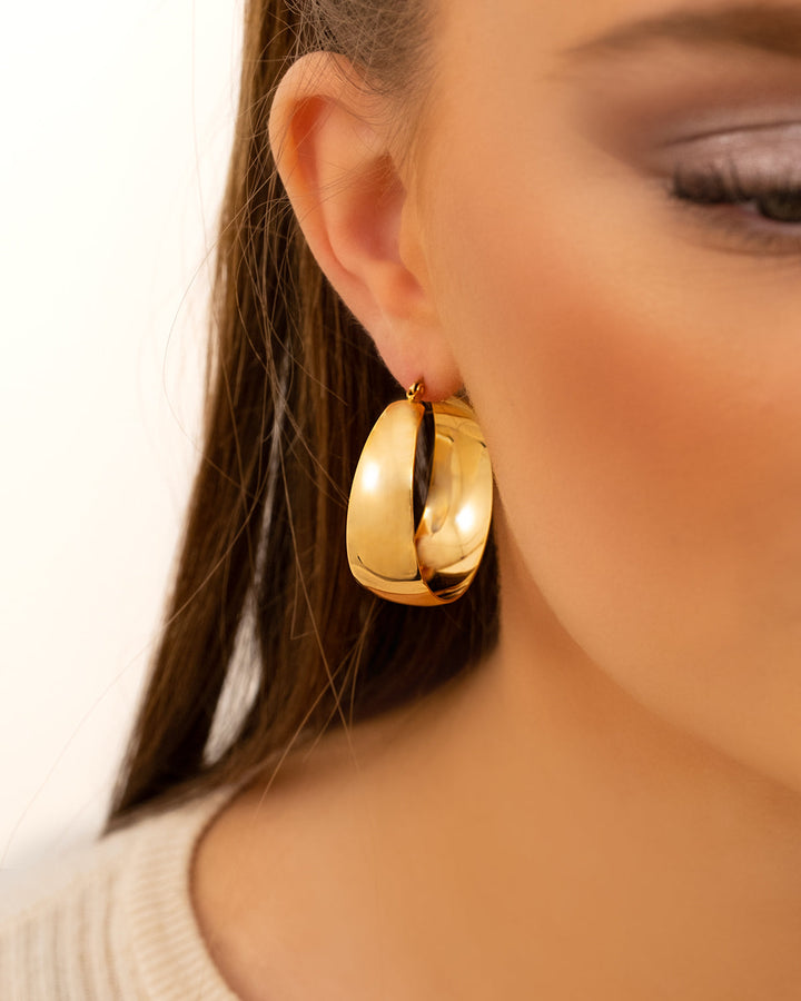 Woman wearing bold gold & silver statement hoop earrings. Stylish and elegant fashion jewelry.