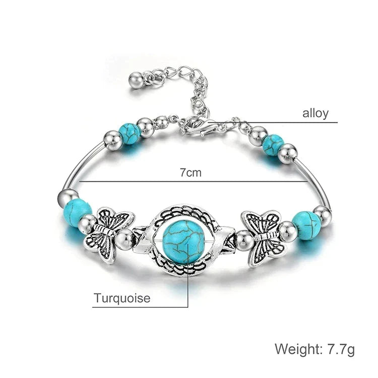 Close-up of a women's turquoise beaded bracelet with detailed silver butterfly charm, a unique accessory.