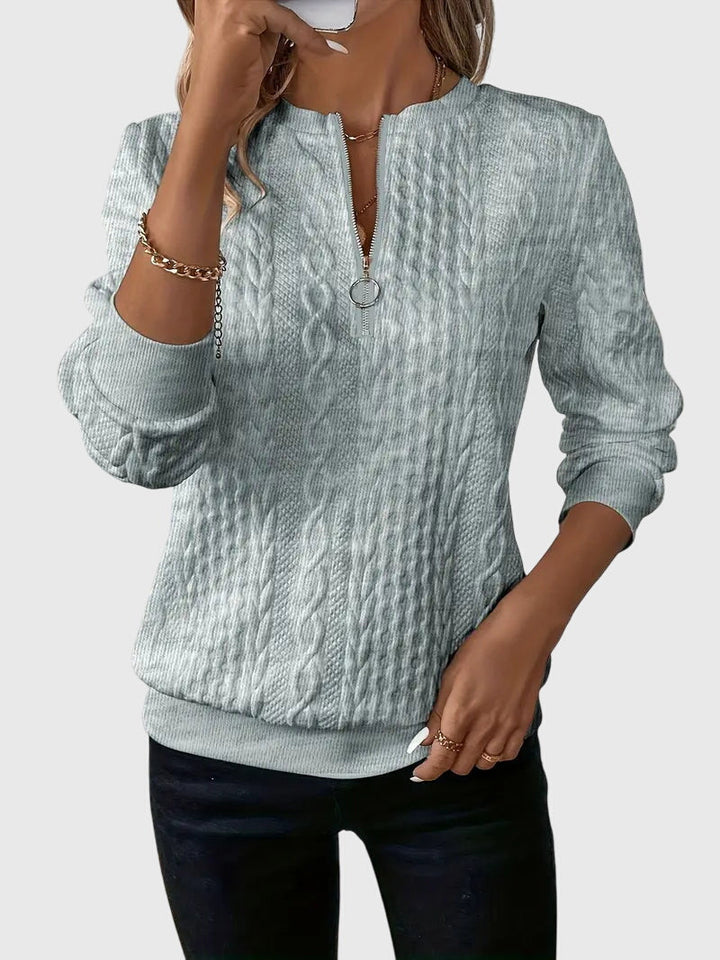 Women's quarter-zip pullover with intricate cable knit texture, designed for comfortable wear.
