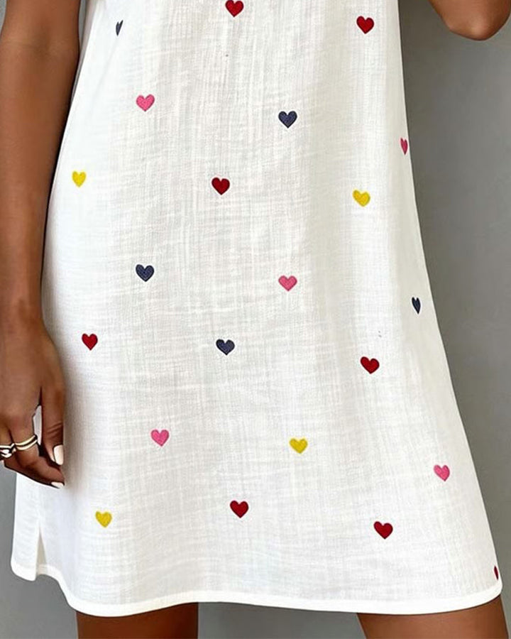 Relaxed fit V-neck mini dress for women, featuring a playful heart print and comfortable puff sleeves. Ideal day dress.