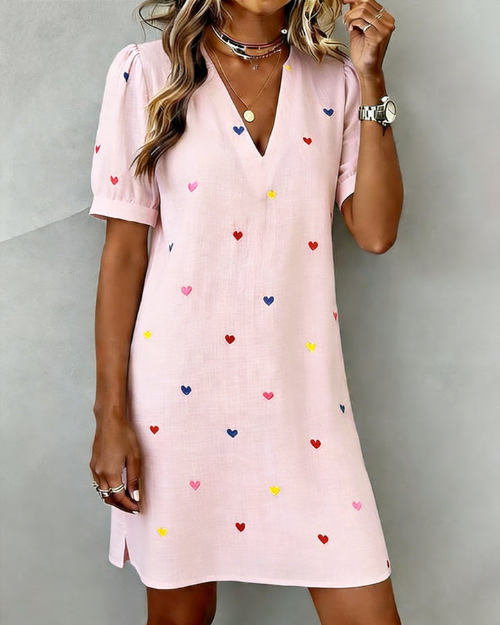 Stylish women's mini dress with all-over heart print, V-neck, and trendy puff sleeves, great for casual outings.