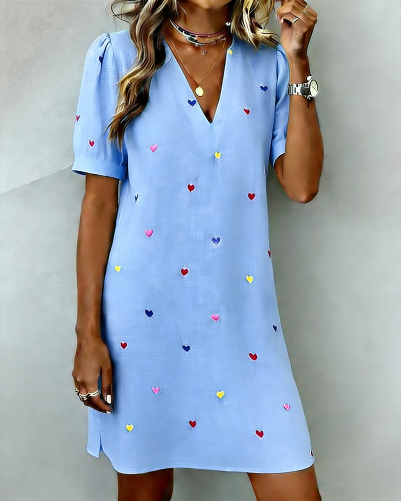 Side profile of a woman in a relaxed fit heart print mini dress, highlighting the puff sleeves and casual style.