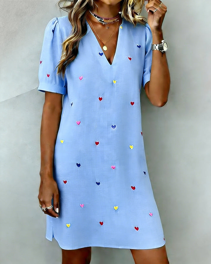 Side profile of a woman in a relaxed fit heart print mini dress, highlighting the puff sleeves and casual style.