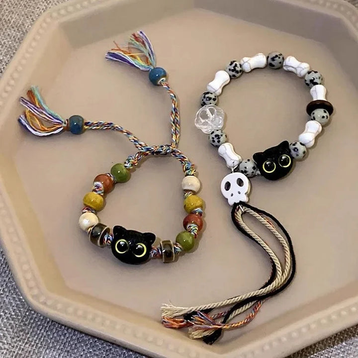 Edgy-cute women's ceramic charm bracelet. Features kitten & skull motifs with bohemian fringe accents.
