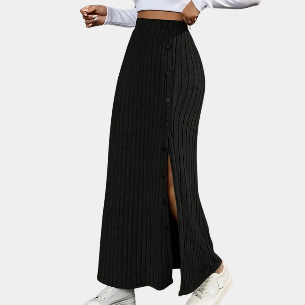 Model wearing a flowing black ribbed knit maxi skirt, styled casually with a white top