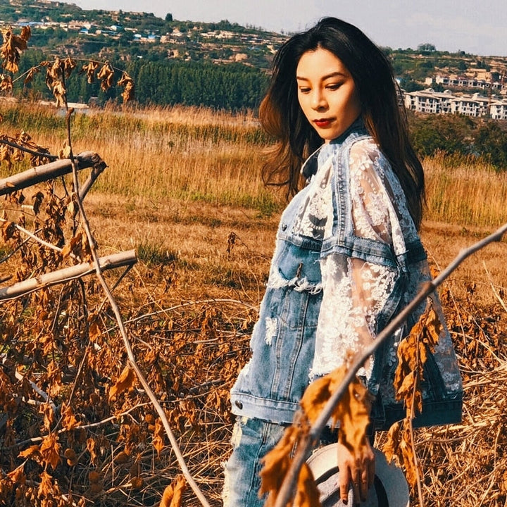 Chic women's blue denim jacket with unique frayed edges, a stylish and versatile layering piece.
